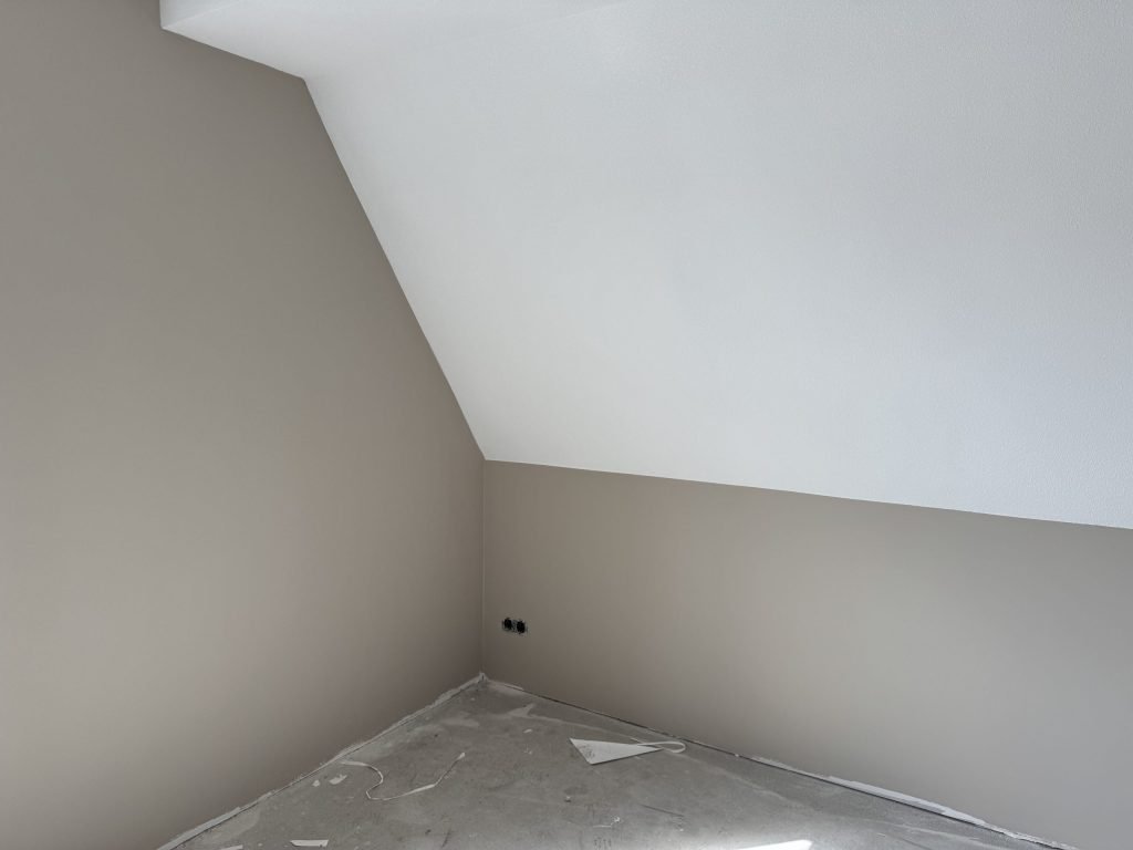 Zolderkamer met een schuine wand en kale wanden, klaar voor de afwerking